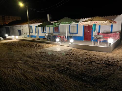 ESTANQUEIRA GUEST HOUSE في سينيس: منزل أمامه طاولة وكراسي في الليل