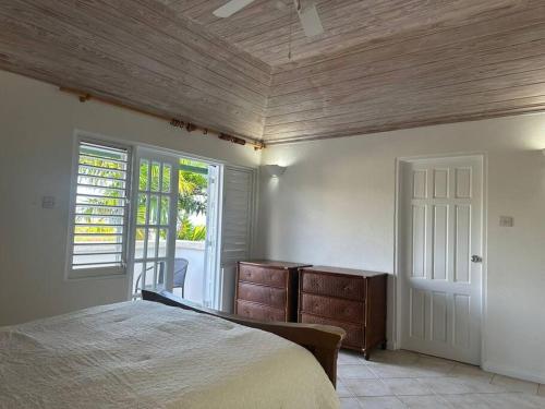 1 dormitorio con cama y techo de madera en Beach Life Villa, en Bridgetown