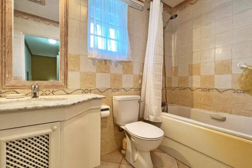 a bathroom with a toilet and a sink and a tub at Beach Life Villa in Bridgetown