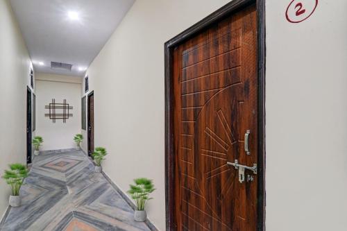 a wooden door in a hallway with potted plants at OYO Flagship 70105 Hotel Pulick Awadh in Lucknow