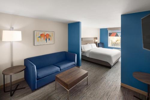 une chambre d'hôtel avec un canapé bleu et un lit dans l'établissement Holiday Inn Express Hotel & Suites Cherry Hills, an IHG Hotel, à Omaha