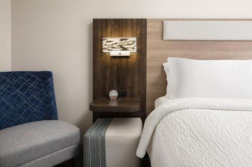 a bedroom with a bed and a chair next to a bed sidx sidx at Holiday Inn Express Hotel & Suites Cherry Hills by IHG in Omaha
