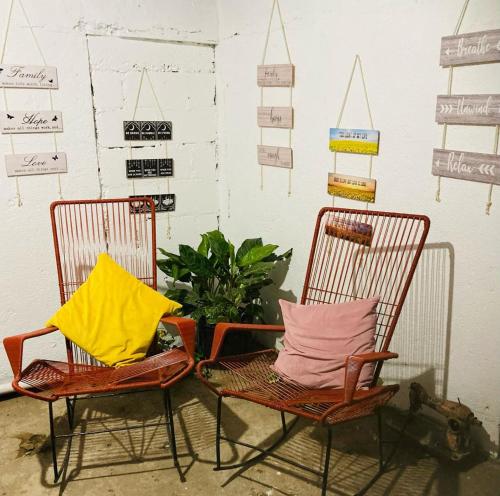 two chairs with colorful pillows sitting next to a wall at Hostel Casa Mar in Liberia