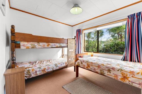 a bedroom with two bunk beds and a window at The Wee Bothy - Whangamata Holiday Home in Whangamata