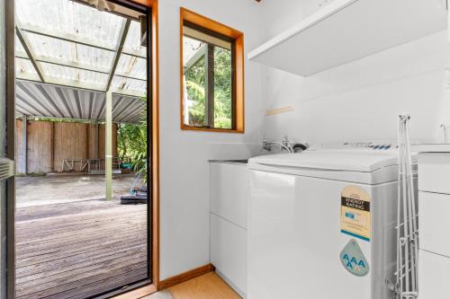 a kitchen with a sink and a sliding glass door at The Wee Bothy - Whangamata Holiday Home in Whangamata