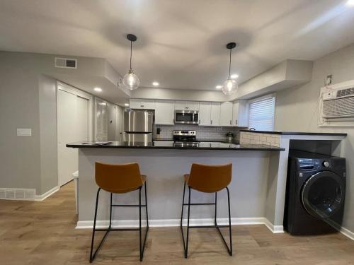 a kitchen with two bar stools at a counter at Joslyn 6-Cozy in Midtown Omaha in Omaha