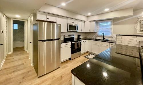a kitchen with a stainless steel refrigerator and white cabinets at Joslyn 6-Cozy in Midtown Omaha in Omaha