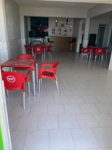 ein Zimmer mit roten Stühlen, Tischen, Tischen und Tisch sowie einem Tisch in der Unterkunft Casa tchitchi in São Filipe