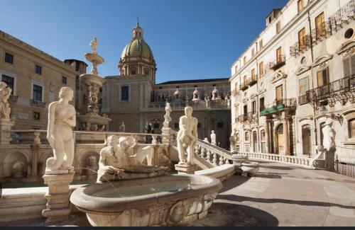 a fountain in the middle of a building with statues at Albergheria little home in Palermo