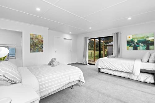 1 dormitorio blanco con 2 camas y ventana en Countryside Guest House, en Tamahere