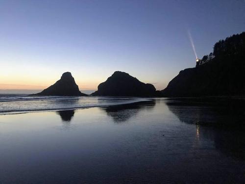 a beach with rocks in the water and the sunset at Breakers - stay in a tiny home on the Oregon Coast in Waldport
