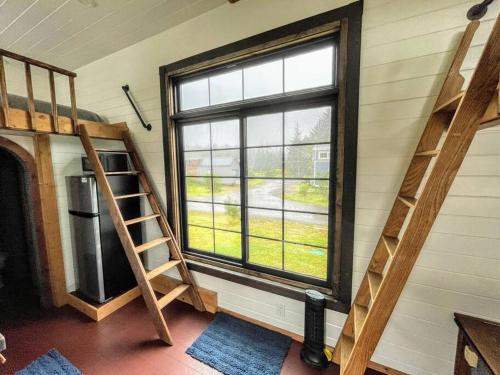 a room with a window and a ladder and a refrigerator at Breakers - stay in a tiny home on the Oregon Coast in Waldport