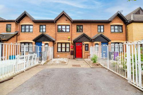 a brick house with a red door and a white fence at Modern House Just Refurbished in London