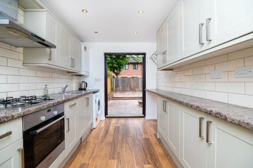 a kitchen with white cabinets and a wooden floor at Modern House Just Refurbished in London