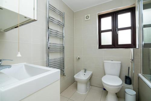 Baño blanco con aseo y lavamanos en Modern House Just Refurbished, en Londres