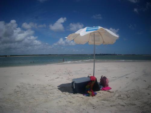 a beach with an umbrella and luggage on the sand at Pousada o Forte in Mangue Sêco