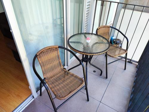 a glass table and two chairs on a balcony at Acogedor Depa en San Miguel in Lima