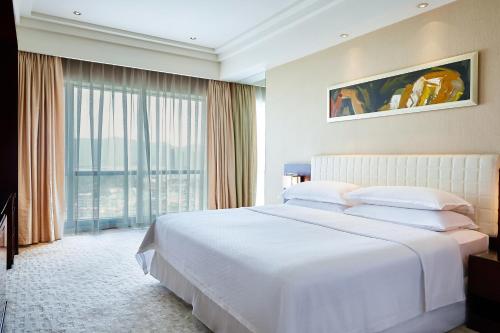 a bedroom with a white bed and a large window at Four Points by Sheraton Hangzhou, Binjiang in Hangzhou