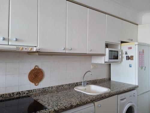 een keuken met witte kasten, een wastafel en een koelkast bij MARE NOSTRUM, PISCINA in Canet de Berenguer