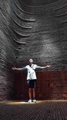 a person standing in front of a brick wall at Cóc Retreat Mỹ Tho City in My Tho