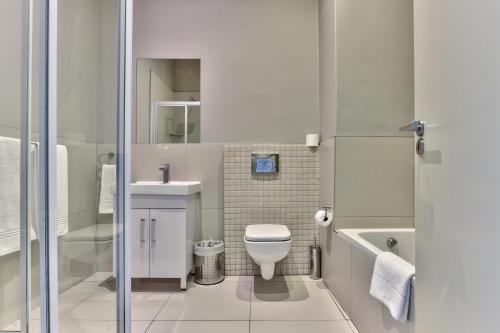 a small bathroom with a toilet and a sink at Heritage Square Apartments in Durbanville