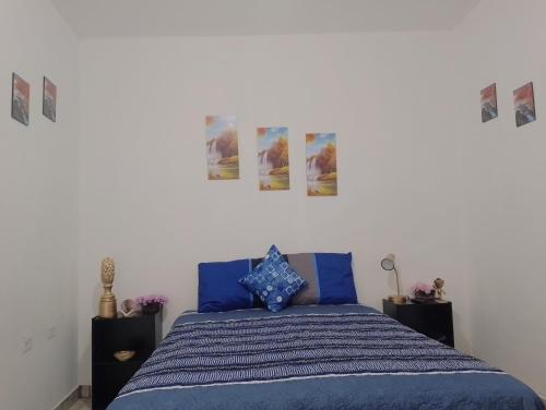 a bedroom with a blue bed with pictures on the wall at MI HOGAR in Tegucigalpa