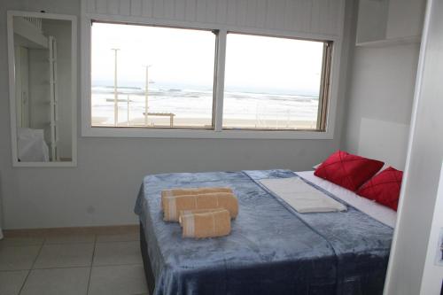 ein Schlafzimmer mit einem Bett mit zwei Handtüchern darauf in der Unterkunft Apartamento Vista para Beira-Mar e Calçadão centro de Tramandaí in Tramandaí