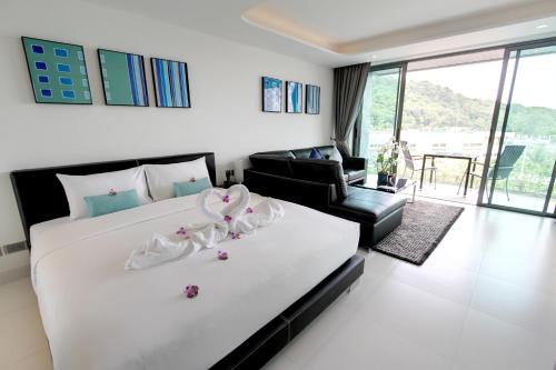 una camera da letto con un grande letto bianco e un divano di Lets Phuket Twin Sands Resort & Spa a Patong Beach