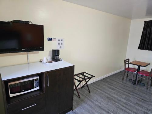 um quarto de hotel com uma televisão e uma mesa e cadeiras em Norvic Motel em Coniston