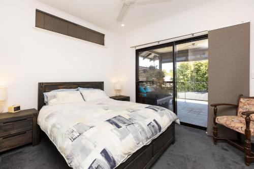 a bedroom with a bed and a chair and a window at Pelcan Gardens Retreat in Broome