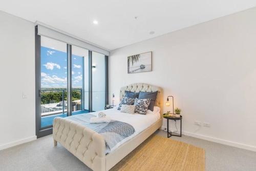 Dormitorio blanco con cama y ventana grande en Vivid home in Bankstown 2B2B, en Bankstown