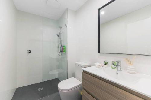 y baño con aseo, lavabo y espejo. en Vivid home in Bankstown 2B2B, en Bankstown
