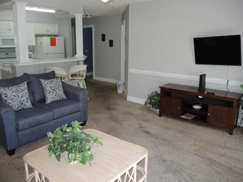 sala de estar con sofá y TV en 1005M condo, en Calabash