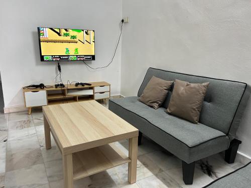 a living room with a couch and a tv at Near 7ELEVE KFC 10pax 3BR Hutan Melintang by willz in Hutan Melintang
