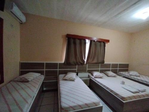 two beds in a room with a window at Hotel novo sol santo amaro in Sao Paulo