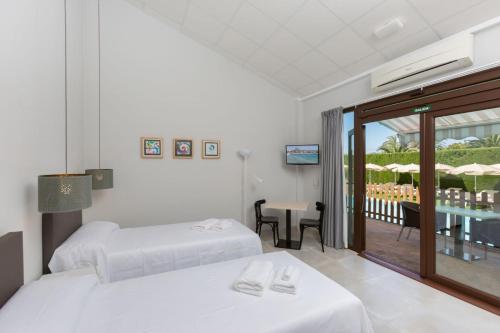a hotel room with two beds and a balcony at Hotel Fortuny javea in Jávea