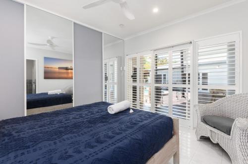 um quarto com uma cama, uma cadeira e janelas em Seabrook beach house em Port Douglas