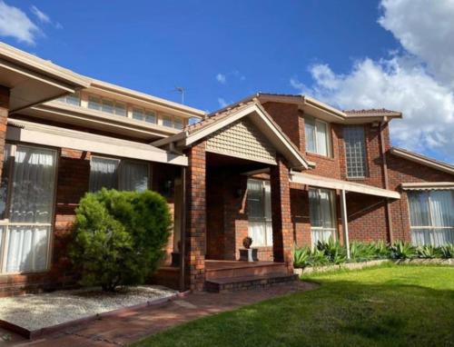 a brick house with a porch and a green lawn at The peaceful retreat in Mulgrave