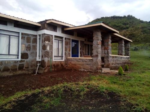 een stenen huis in een veld met een berg op de achtergrond bij Heaven's Gate in Nakuru