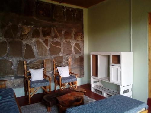 une chambre avec deux chaises et un mur en pierre dans l'établissement Heaven's Gate, à Nakuru