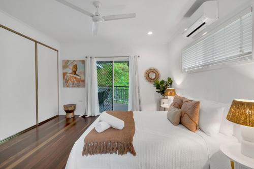 a white bedroom with a white bed and a window at 'Tropical Refuge' Classic Queenslander Paradise in Stratford