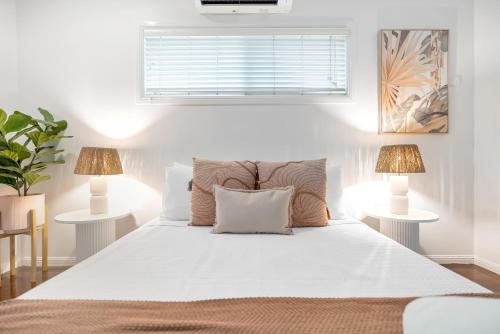 a bedroom with a large white bed with two lamps at 'Tropical Refuge' Classic Queenslander Paradise in Stratford
