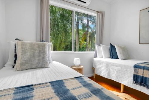 two beds in a room with a window at 'Tropical Refuge' Classic Queenslander Paradise in Stratford