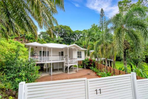 a white fence in front of a house with palm trees at 'Tropical Refuge' Classic Queenslander Paradise in Stratford