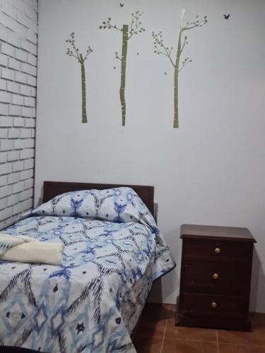 a bedroom with a bed and trees on the wall at Zeus cómodo e Imperdible in Cochabamba