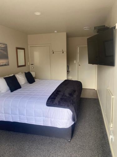um quarto com uma cama grande e uma televisão de ecrã plano em Ashbury Park Motel em Timaru