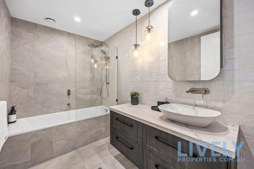 a bathroom with a sink and a tub and a mirror at Beach Street Luxury 3 Bed with Beach & Bay Views in Melbourne