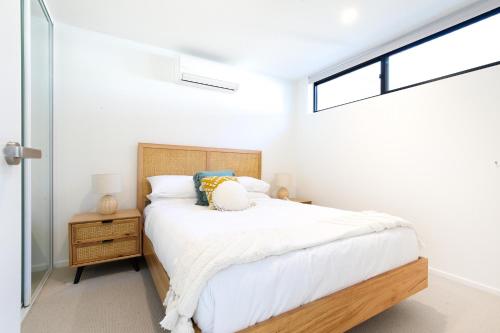 Habitación blanca con cama y ventana en Exquisite 1-Bed Apartment with Bay Views, en Batemans Bay
