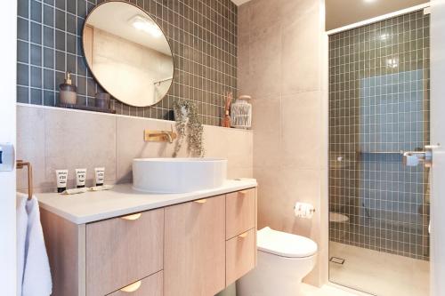 y baño con lavabo, espejo y ducha. en Exquisite 1-Bed Apartment with Bay Views, en Batemans Bay