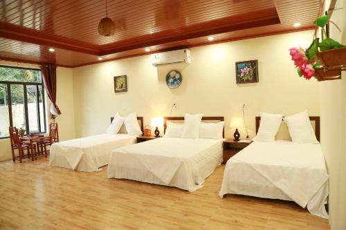 a bedroom with two beds with white sheets at Son River House in Phong Nha